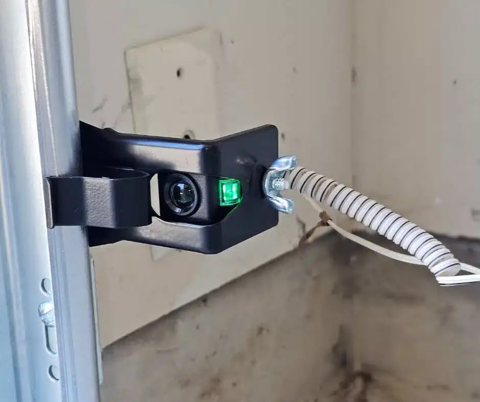 Residential garage door safety sensor mounted beside the track