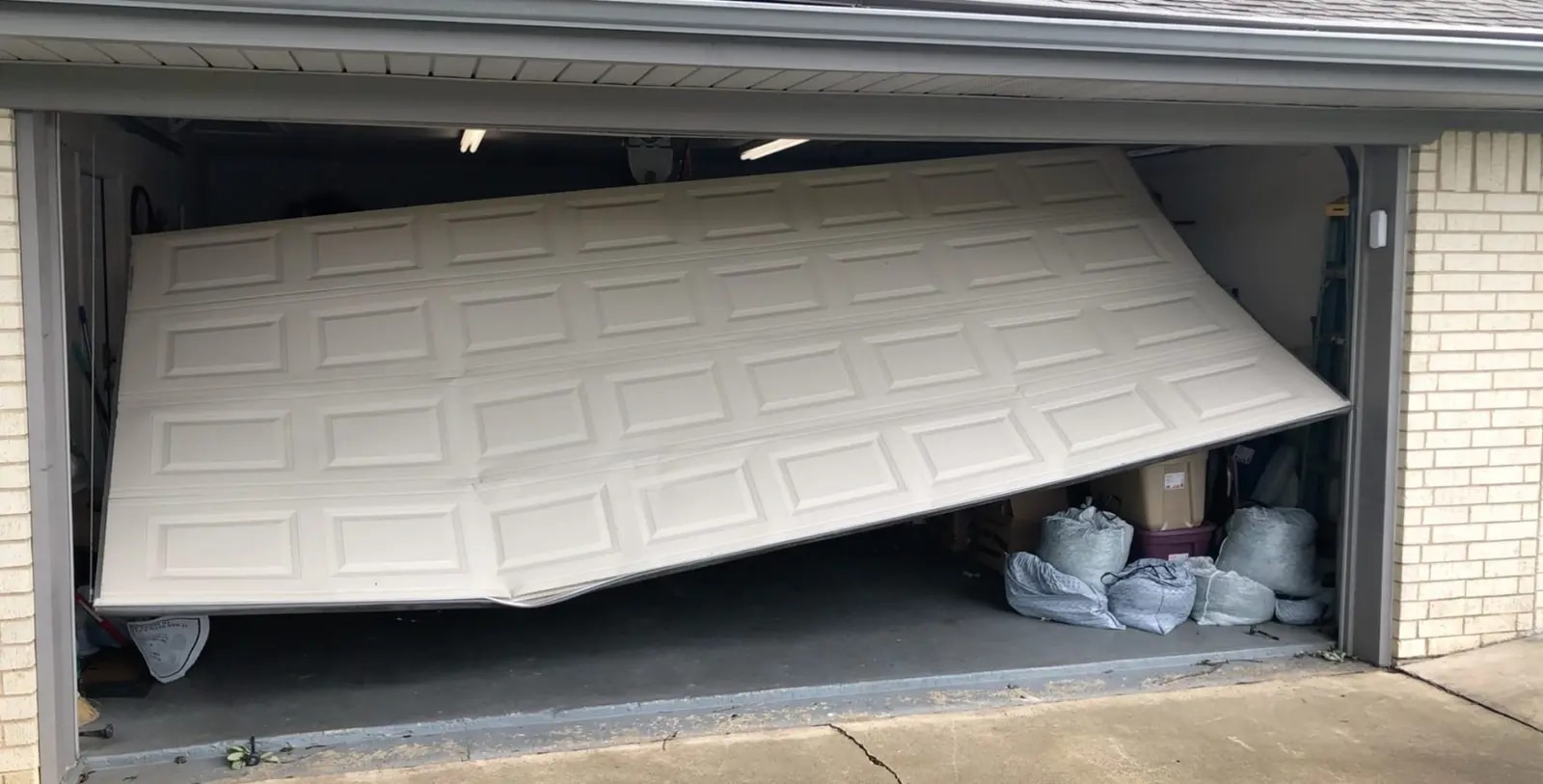 Residential garage door sitting crooked after moving out of its tracks