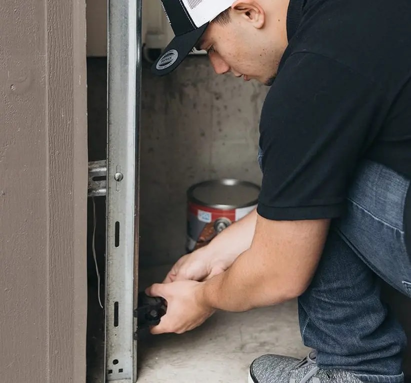 Spot On Garage Door technician inspecting the lower track and safety hardware
